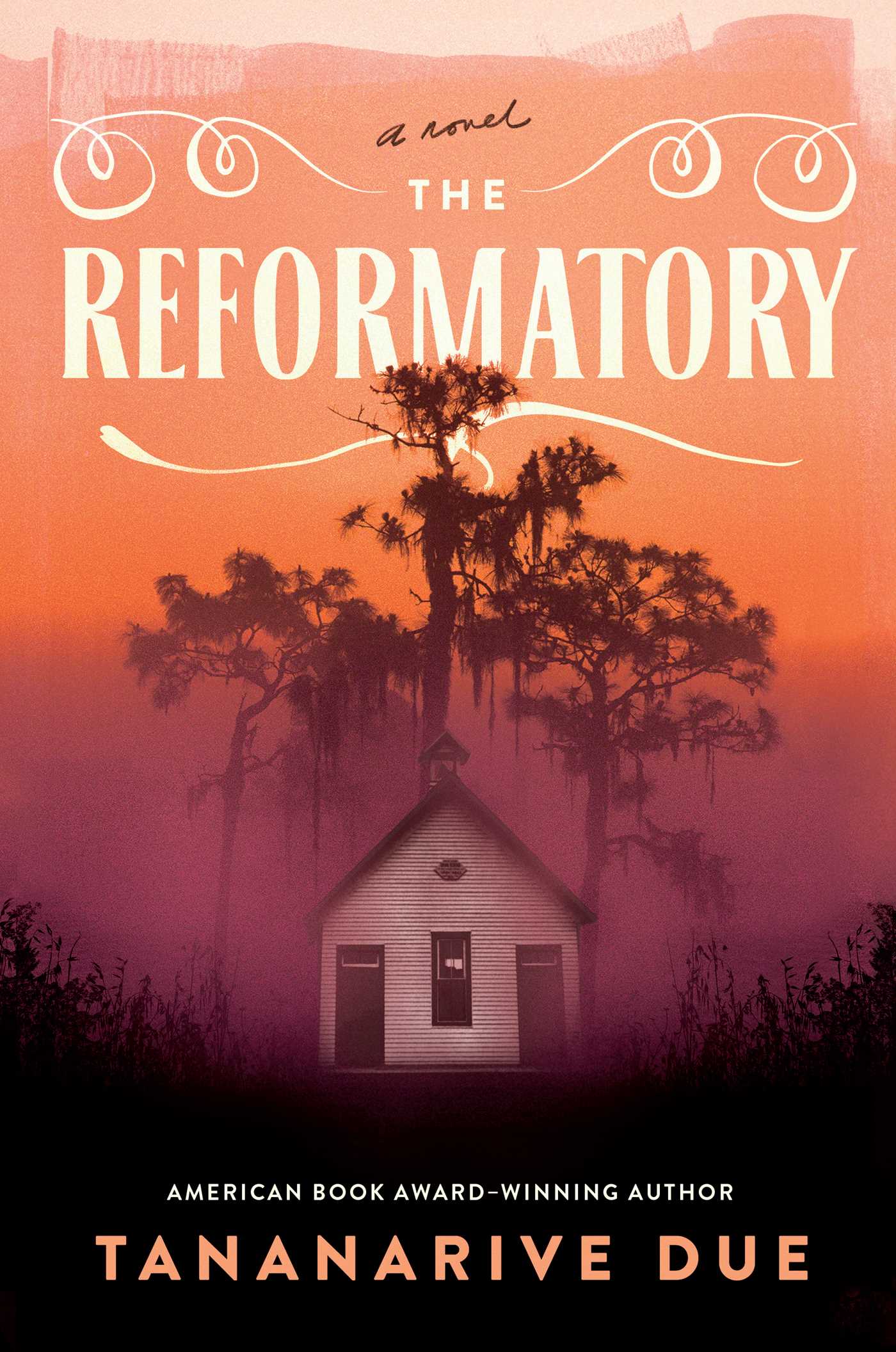 Book cover for The Reformatory by Tananarive Due. The title is in white all caps in front of an orange sky, like a sunset. In the foreground is a white shack shrouded by mist in front of a large evergreen tree.